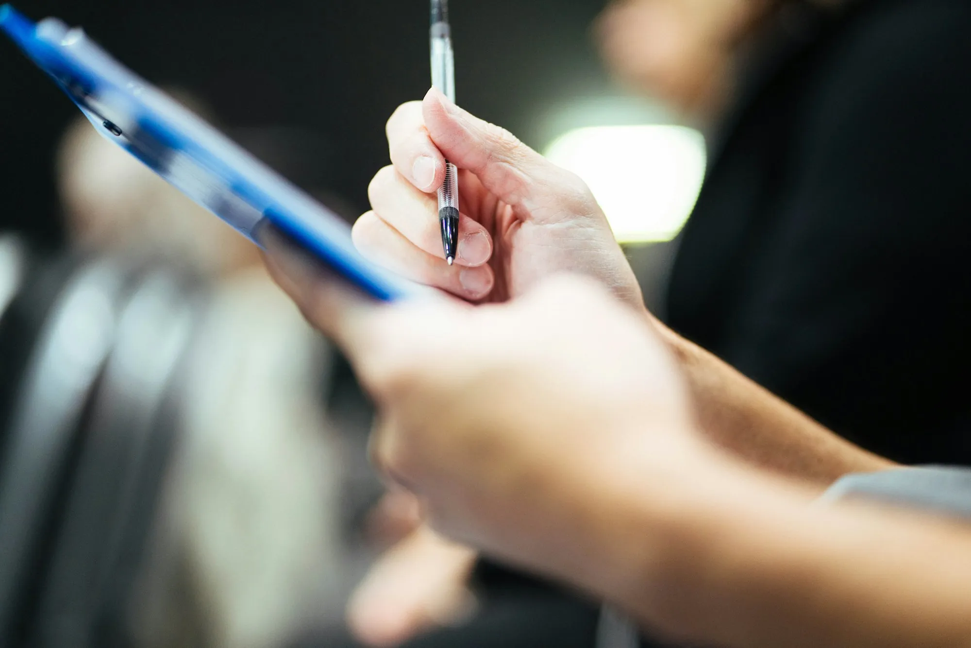 Hand filling out a form on a clipboard